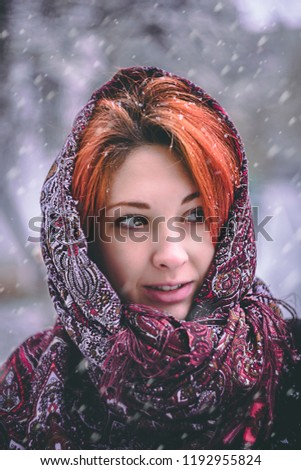 Portrait of a woman in a cold winter. Portrait of woman in winter clothing looking at camera in snowy park.