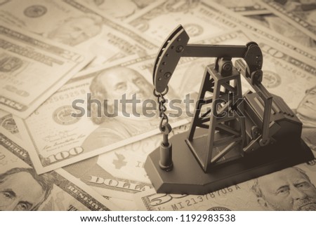 Spending or investment of a country's revenues from petroleum exports industry (Petrodollar). Oil pump jack on US dollar banknotes. Concept of crude oil production, petroleum industry or petrodollar.