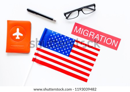 Immigration to United States of America concept. Textimmigration near passport cover and USA flag on white background top view