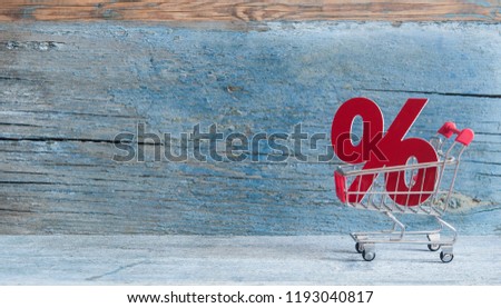 Shopping cart and sign percent with sale concept on wood background 