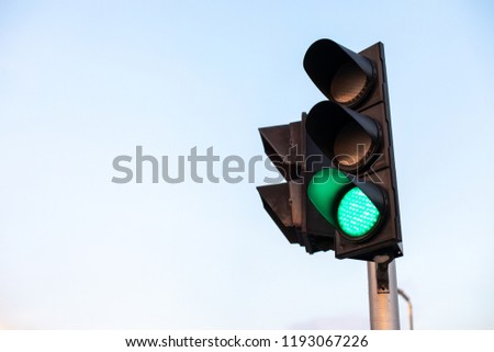 Green traffic light on blue sky background.