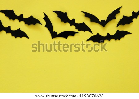 Halloween holiday concept. Black bats over yellow background. Top view, flat lay