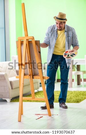 Young male artist working on new painting in his studio