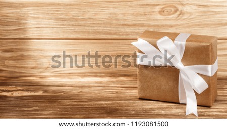 Gift box with white ribbon on wooden background top view. New year and Christmas holiday concept. Flat lay with copy space. Discount gift for sale day.
