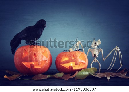 Halloween holiday concept. Pumpkins and bat on wooden table