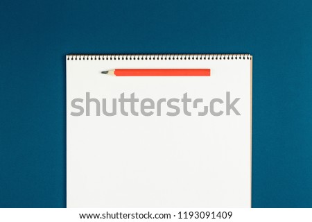 notebook with pencil on blue background top view, schoolboy doing homework, desk of office worker flat lay. empty notepad on table