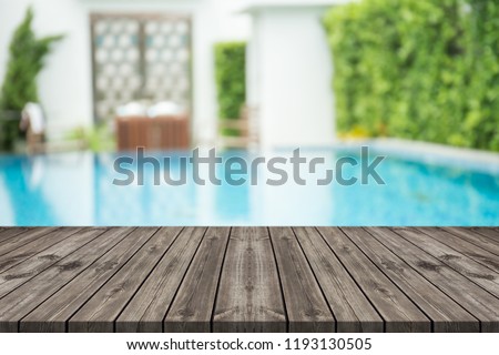 Empty wooden table in front with blurred background of swimming pool  Royalty-Free Stock Photo #1193130505