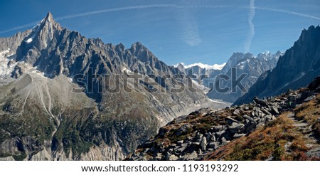 A glacier valley in the region of Chamonix in the alps of France. High alpine snow covered mountains surround the foreground rocks and alpine terrain.