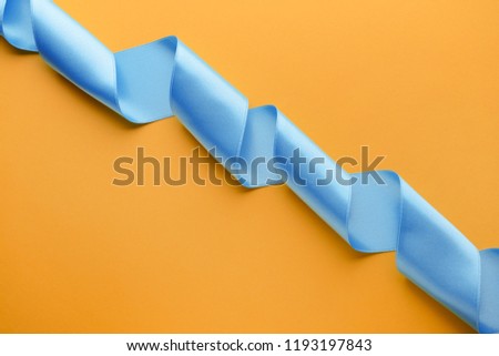 Curled blue ribbon on color background
