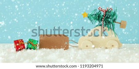 Wooden car carrying a christmas tree in front of blue background
