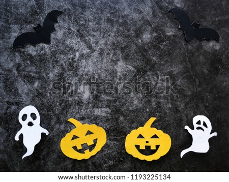 Halloween concept with pumpkins, ghosts and bats cut paper on black concrete background.