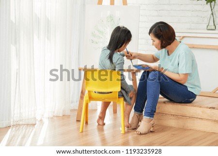 Mother and daughter painting together at home