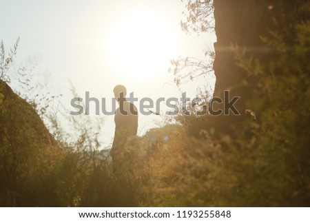 Silhouette of a man in a hollow, among mountains, grass, in a valley, sunlight behind, sunset, hiking alone. A man walks, leads a healthy lifestyle, stopped, stands Royalty-Free Stock Photo #1193255848