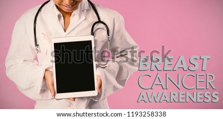 Breast cancer awareness message against smiling nurse wearing breast cancer awareness pink ribbon looks at her tablet