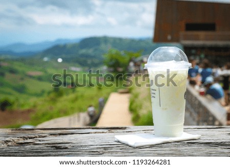 Iced milk  in plastic cup on wood  table in nature