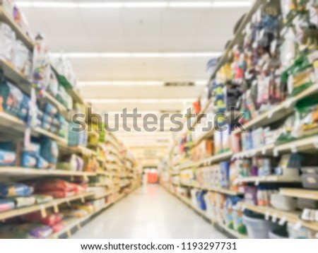 Blurred abstract low angle view dog and cat food shelves at American supermarket. Defocused pet supplies, laundry, dish soap, cat litter, pet and home care aisle row display with price tags