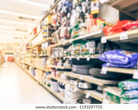 Abstract blurred dog and cat food shelves at American supermarket. Defocused pet supplies, laundry, dish soap, cat litter, pet and home care aisle row display with price tags.