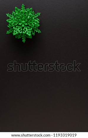 Green snowflake ornament on the up-left corner of a black background