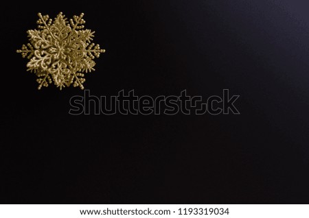 Close-up of a golden snowflake ornament on the up-left corner of a black gradient background