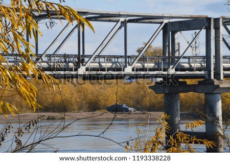 The picture about industry and nature with bridge support on the riverside and a car