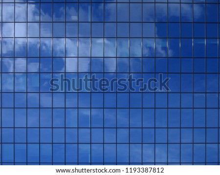 The wall of the building is made of glass. Reflection of the sky in the building