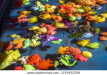 Multicolored plastic fish swim on the surface of the water