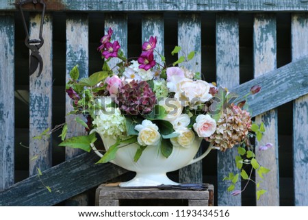 Floral composition, beauty bouquet in antique faience vase, secateurs  on aged wooden fence , outdoor and space, vintage style, daylight