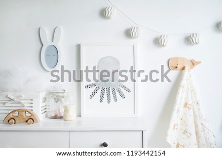 The modern sandinavian newborn baby room with mock up poster frame, wooden car, boxes and small mirror. Minimalistic and cozy interior with white walls.