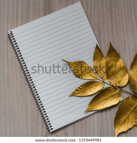 Notepad and golden maple leaves on a wooden background, copy space.