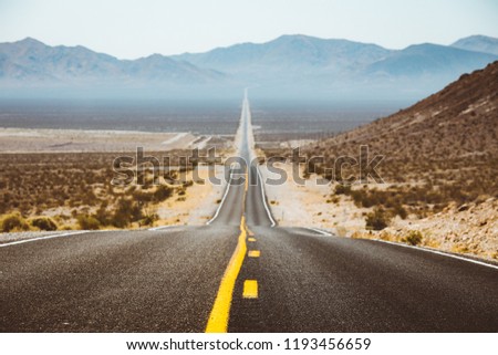 Classic panorama view of an endless straight road running through the barren scenery of the American Southwest with extreme heat haze on a beautiful sunny day with blue sky in summer Royalty-Free Stock Photo #1193456659