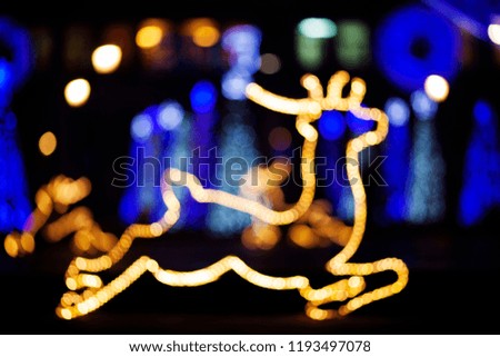 Glowing silhouette of a deer on a Christmas decorated street, blur
