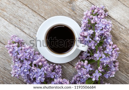 Blooming lilac and fresh coffee in a white cup.