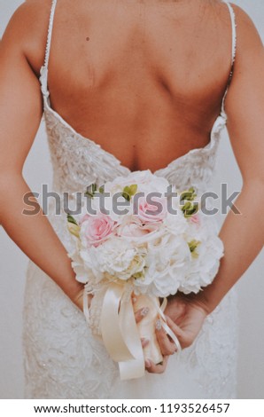women in a wedding dress with her back holds a bouquet of flowers in her hand , wedding photo, body