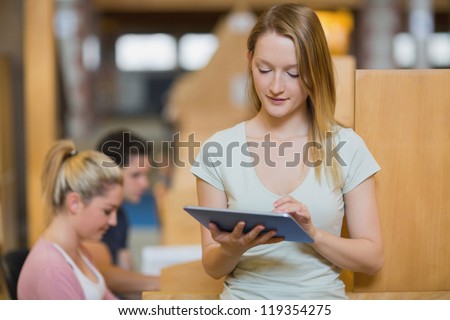 Woman standing holding a tablet pc at the college library