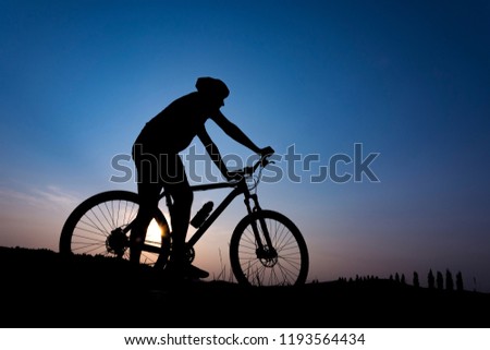 Silhouette of boy on the bike. Young cyclist is jumping on his bike during sunset. Royalty-Free Stock Photo #1193564434