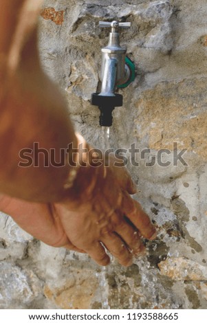bright close up beautiful photo of young man washing his strong hands on outside stone tap