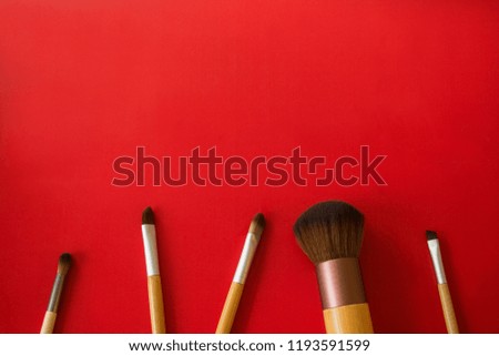 Make-up brushes are placed on a red background.