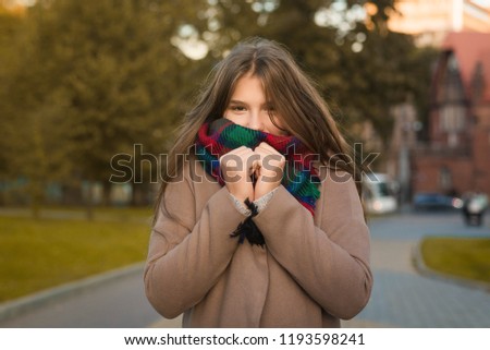 Portrait of a beautiful girl in park. Teenage girl covering face with woolen scarf and brown coat. Close up photo. Young student have fun. Lifestyle photo. beautiful girl freezing in park, cold autumn