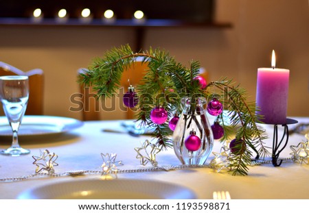 Table with christmas decoration in purple colors.  A colorful laid table decorated different in purple with xmas decoration for a christmas dinner in the dining-room indoors at home