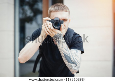 Close up of attractive man photographer making photos of modern building.