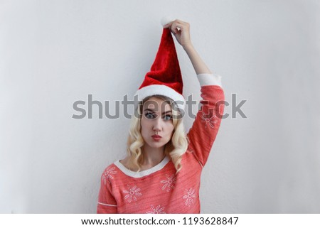 Beautiful blonde girl in christmas hat have fun. On a light background