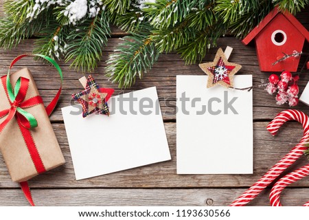 Christmas blank photo frames, birdhouse decor and snow fir tree on wooden table. Top view with space for your greetings
