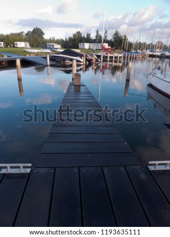 Sunrise at the harbor of Koudum in Netherlands. The clouds, trees and masts are reflected in the water. Royalty-Free Stock Photo #1193635111