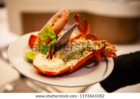 Simple yet delicious. Hot and freshly baked halved Lobster with butter. Fresh, juicy, tasty and flavorful bright red Maine Lobster or American lobster on a hand of waitperson, ready to be served. Royalty-Free Stock Photo #1193661082