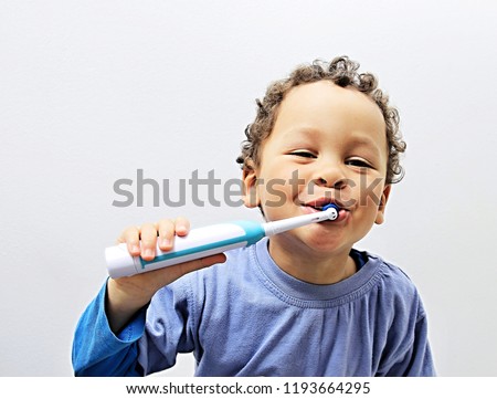 little boy brushing his teeth with an electric tooth brush stock image with grey background stock photo Royalty-Free Stock Photo #1193664295