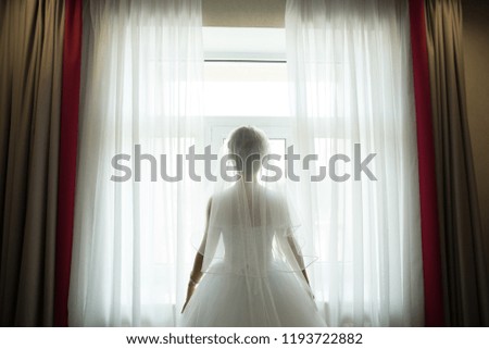 girl standing near the window in a wedding dress