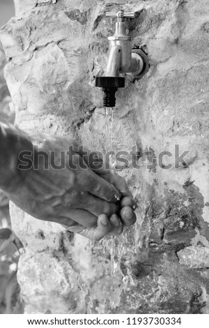 black and white bright close up beautiful photo of young man washing his strong hands on outside stone tap