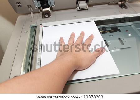 hand pressing paper on a copy machine