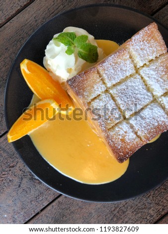 Beautiful dessert background. Toast with egg yolk sauce decorated with whipped cream and slices of orange,