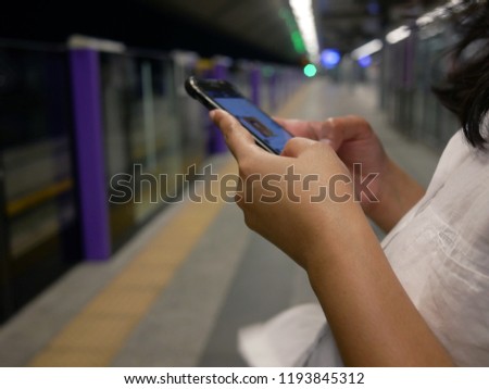closeup of hand woman using smartphone at train station.